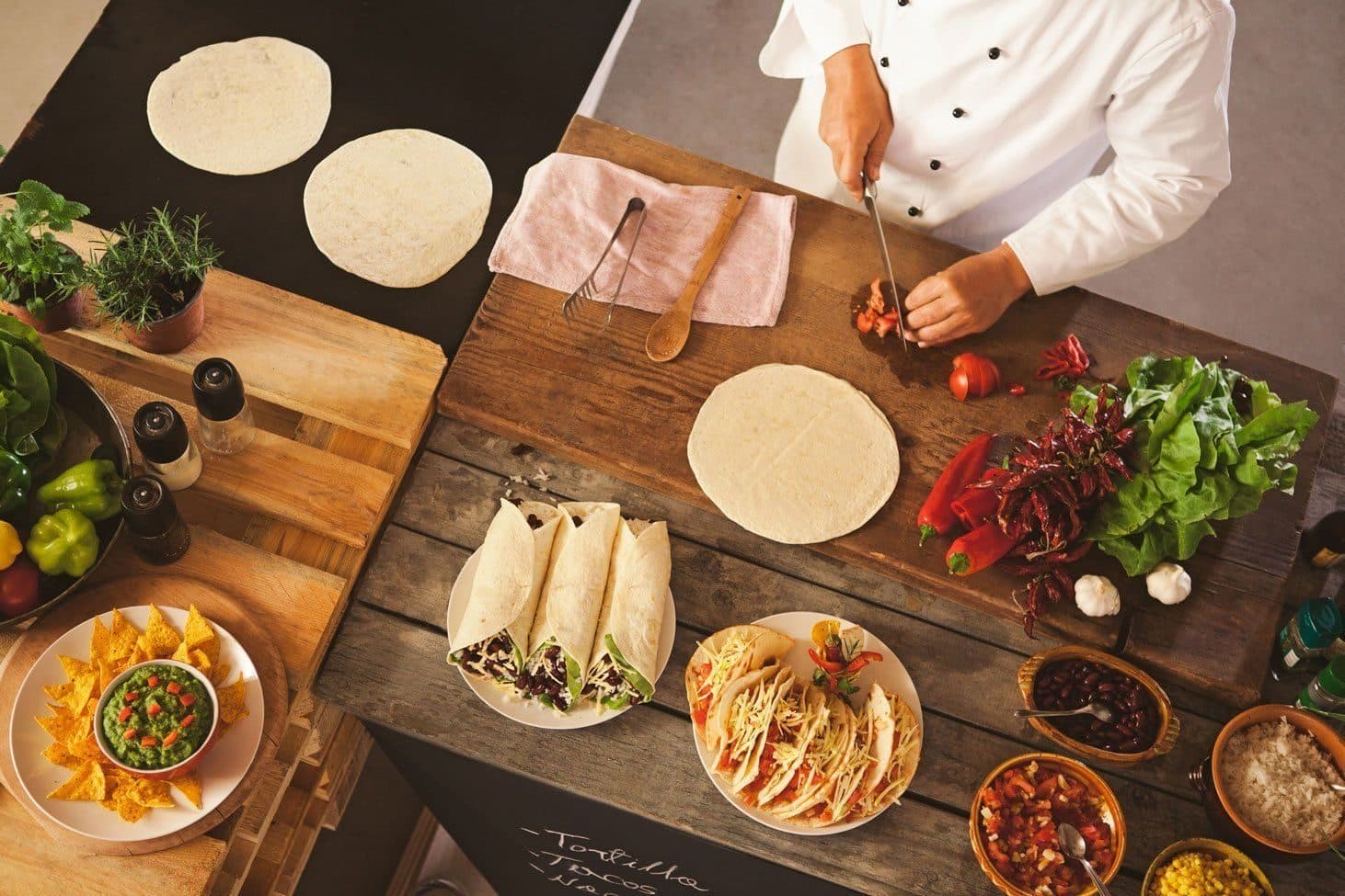 Un chef preparando tacos sobre una tabla de madera